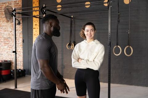 Urban gym coaching with diverse trainer consulting female member by pull-up rig and rings