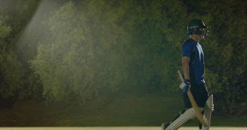 Night cricket batsman walking off pitch holding bat african american player in helmet