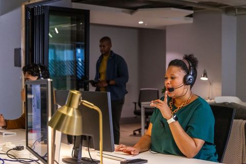 Customer support specialist speaking into headset in modern open-plan office environment