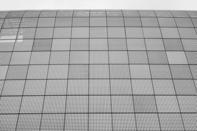 Abstract metallic grid pattern on a modern building facade. Can be used for architectural presentations, urban design concepts, and artistic backgrounds showcasing contemporary and geometric designs. The image represents clean lines and modern aesthetics suitable for illustrating themes of innovation and modern industrial aesthetics.