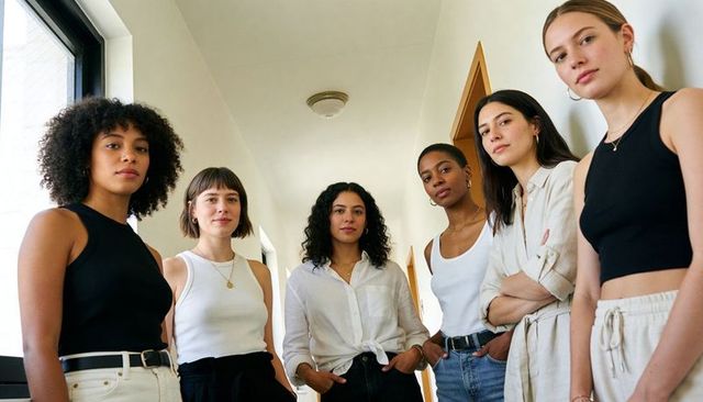 Diverse young women standing together in bright minimalist hallway, confident casual portrait
