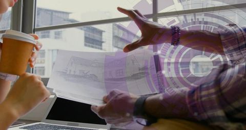 Architects collaborating over residential sketches and laptop, hands pointing at plans