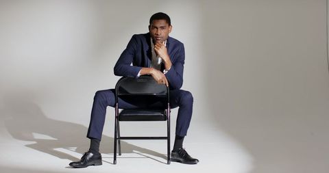 Confident professional in suit sitting on chair backrest
