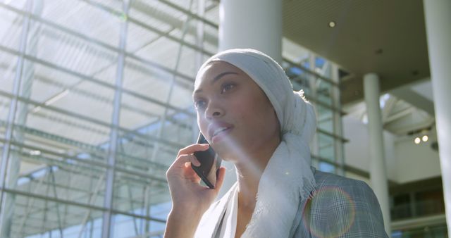 Professional Woman in Hijab Talking on Smartphone in Modern Office Building - Download Free Stock Images Pikwizard.com