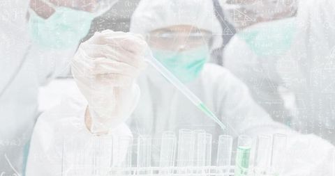 Gloved scientist dispensing green reagent into test tubes with pipette wearing PPE