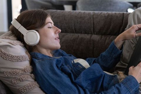 Relaxing on couch with headphones and tablet, young woman lounging at home