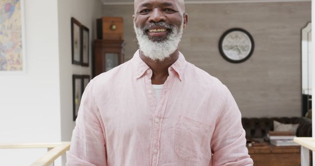 Portrait of happy senior african american man wearing pink shirt smiling at home. Senior lifestyle and domestic life, unaltered.