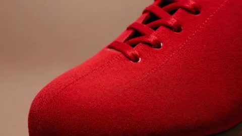 Camera sliding across red suede shoe toe and laces — closeup texture and stitching