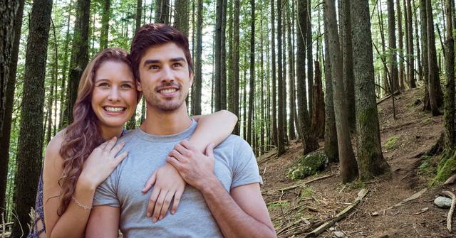 Young couple embracing and looking into the distance amidst a dense forest. Suitable for themes of love, nature, adventure, and togetherness. Ideal for advertisements, social media posts, relationship or travel blogs, and website banners promoting outdoor activities or romantic getaways.