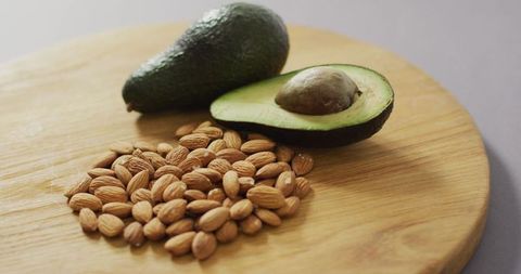 Almonds and avocado on wooden board showcasing plant-based diet