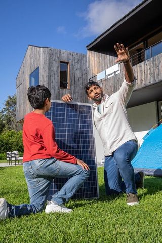 South Asian Father and Son Installing Solar Panel Outdoors
