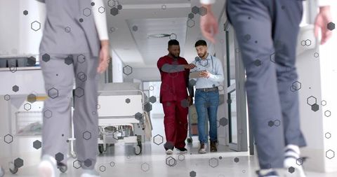 Healthcare Team Walking and Examining Tablet in Bright Hospital Corridor with Gurney