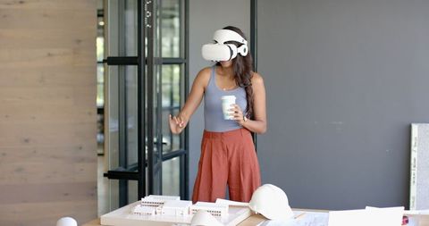 Woman Using VR Headset with Architectural Model in Modern Office