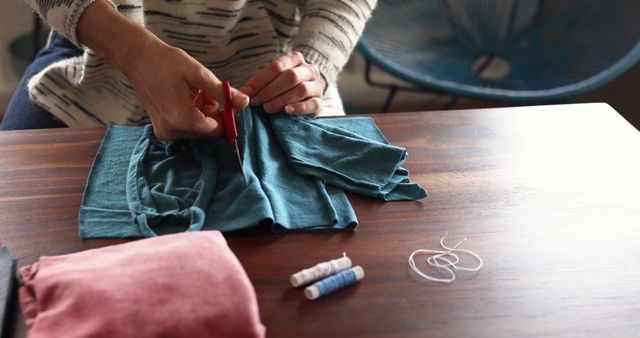 Person upcycling old clothes with scissors and thread on table - Download Free Stock Images Pikwizard.com