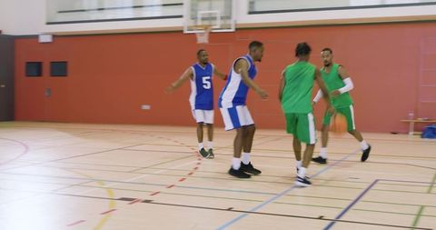 African american basketball players dribbling and faking defender on indoor court action
