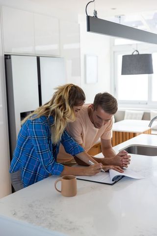 Couple collaborates signing documents at marble kitchen island