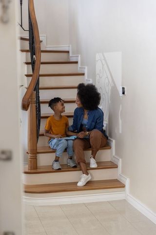 Mother and son bonding on curved wooden stairs reading notebook together