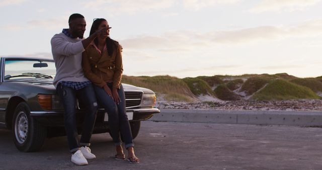 African american couple pointing towards a direction while standing on the road. road trip travel and adventure concept