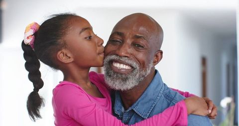 African american grandfather embracing granddaughter kissing cheek closeup family moment