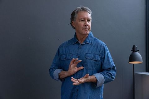 Senior Man Gesturing While Explaining Concept in Minimalist Studio
