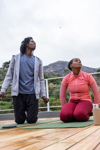 African american couple practicing outdoor yoga on deck with mountain view morning stretch
