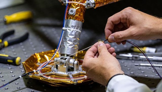 Hands assembling multi-pin connector on kapton-wrapped robotic joint for precision systems