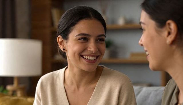 Smiling women having warm conversation on sofa in cozy neutral living room