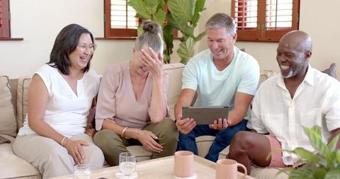 Diverse Friends Enjoying Time Viewing Tablet in Cozy Living Room