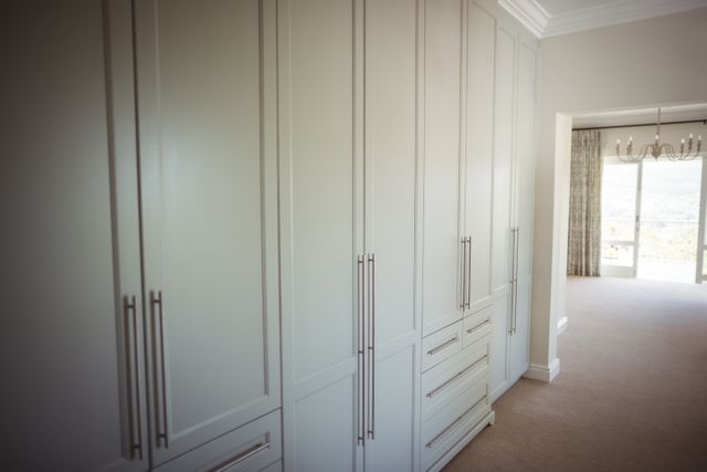 Modern luxurious wardrobes in a spacious interior with white cabinetry and sleek handles. Ideal for showcasing contemporary home design, storage solutions, and elegant living spaces. Perfect for use in home decor magazines, real estate listings, and interior design portfolios.