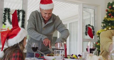 Senior Man Carving Roast at Christmas Family Gathering in Festive Setting