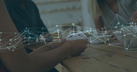 Friends playing cards at wooden table with abstract network overlay representing social connectivity