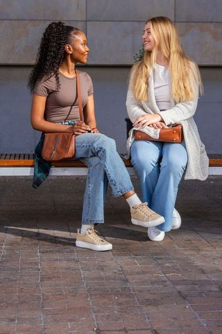 Diverse young women sitting on bench chatting smiling urban friendship lifestyle fashion