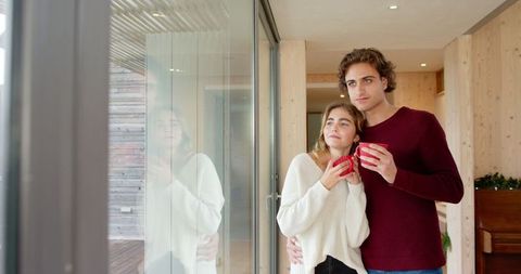 Couple Relaxing Indoors with Hot Drinks by Large Window