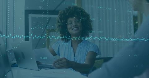 Smiling advisor reviewing documents with client in home office with laptop and data overlay