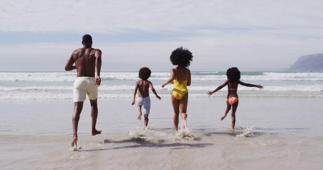 African american parents and two children running at the beach. family outdoor leisure time by the sea.