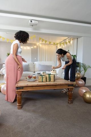 Diverse Friends Arranging Cake and Gifts in Cozy Living Room