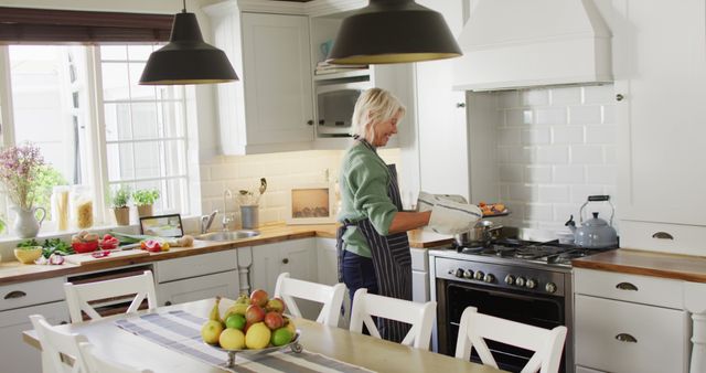Happy senior caucasian woman standing in kitchen and preparing dinner - Download Free Stock Photos Pikwizard.com