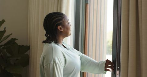 African american woman opening sliding glass door in bright minimalist home interior