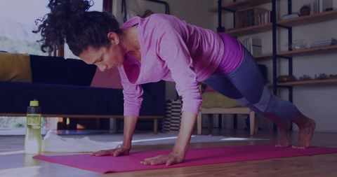 Woman Practicing Plank Pose on Pink Yoga Mat in Living Room