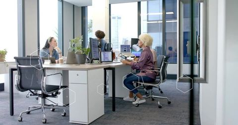 Diverse Team Collaborating at Open-Plan Office Desk Using Laptops and Monitors