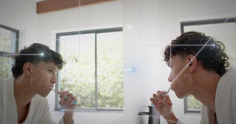 Young man brushing teeth in modern minimalist bathroom mirror reflection natural light