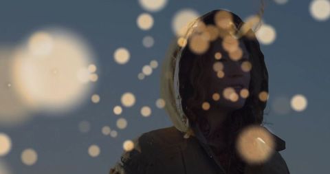 Woman in hooded parka with bokeh against dusk sky