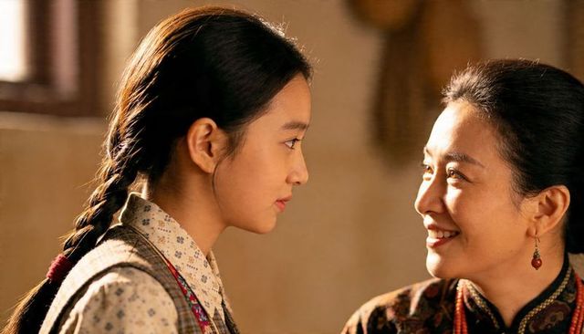 Smiling mother and teen daughter sharing sunlit quiet moment at home, braided hair