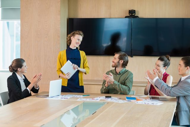 Business team applauding their colleague in conference room at office