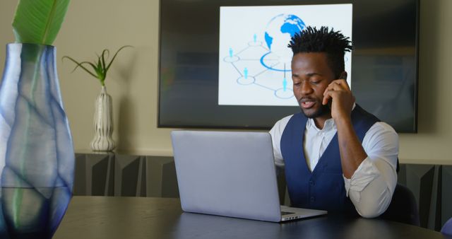 Confident Businessman Working on Laptop and Taking Phone Call in Modern Office - Download Free Stock Images Pikwizard.com