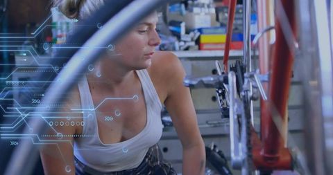 Woman mechanic repairing red bicycle drivetrain with tech overlay in workshop