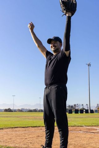 Baseball player celebrating catch with arms raised on sunny field, motion hud overlay