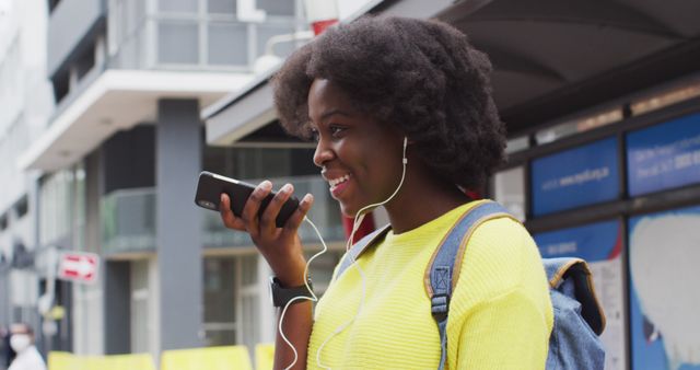 Afro-American woman listening to music via smartphone at urban bus stop - Download Free Stock Images Pikwizard.com