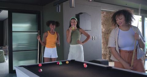 African american friends playing pool in modern home lounge with black felt table