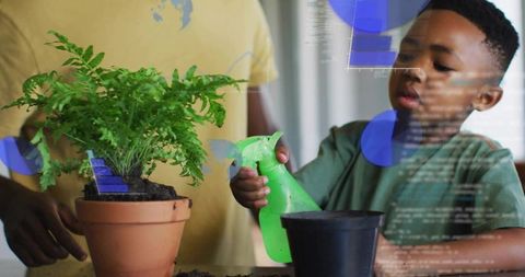 Child watering potted fern with spray bottle while parent guiding indoor gardening